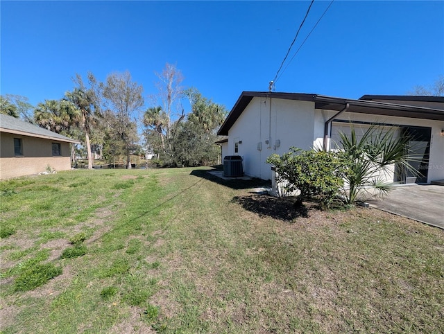 view of property exterior featuring central AC unit, a garage, a yard, driveway, and stucco siding