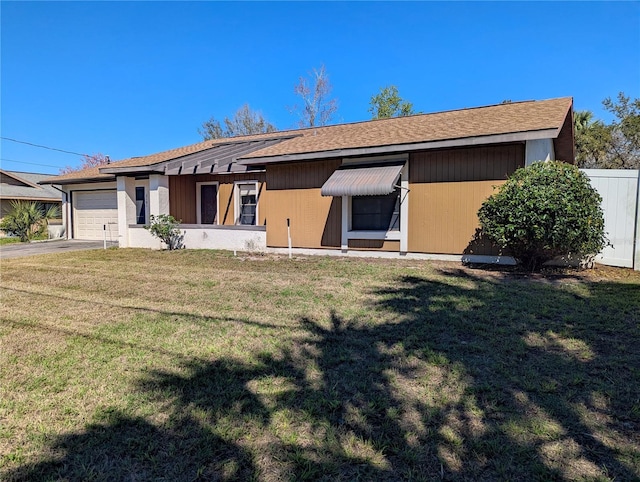 view of front of house with a front lawn, driveway, an attached garage, and fence