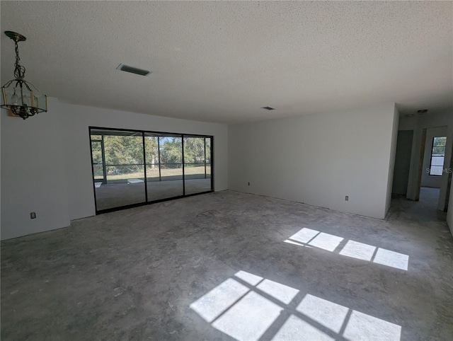 unfurnished room featuring a textured ceiling, a wealth of natural light, and visible vents