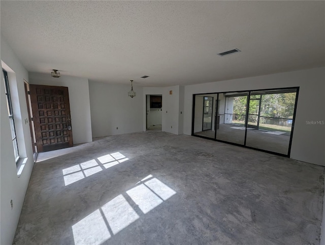 unfurnished room with a textured ceiling, visible vents, and unfinished concrete floors