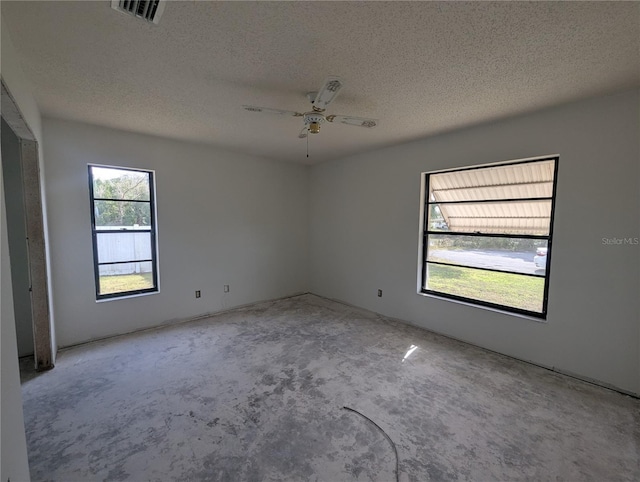 spare room with a ceiling fan, visible vents, and a textured ceiling