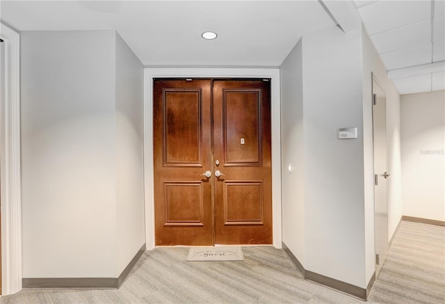 hall featuring baseboards and light colored carpet