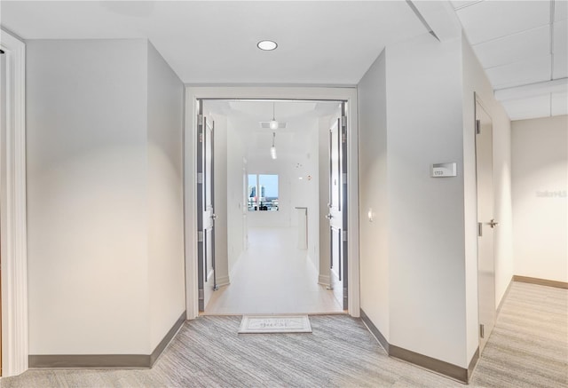 hallway with light colored carpet and baseboards