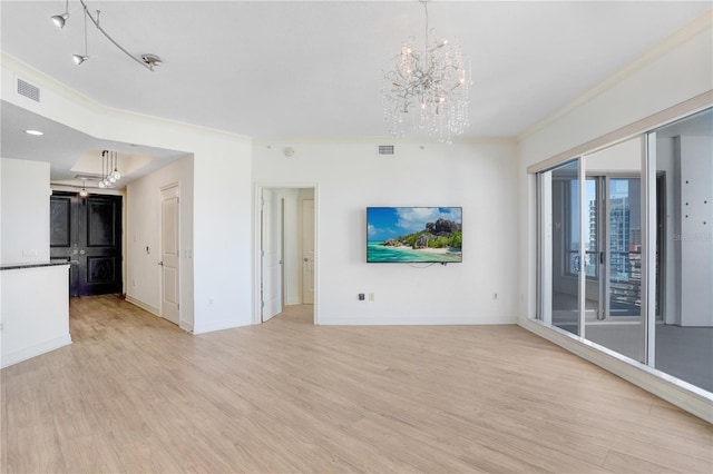 unfurnished living room featuring a chandelier, light wood-style flooring, visible vents, baseboards, and crown molding