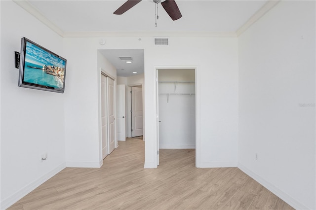 unfurnished bedroom with light wood finished floors, baseboards, visible vents, and crown molding