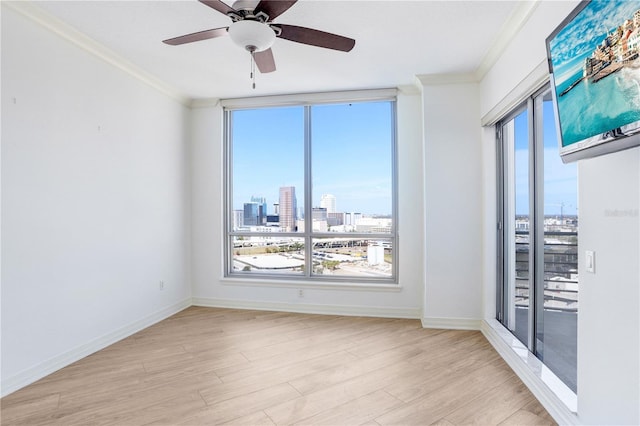 empty room featuring ornamental molding, baseboards, and wood finished floors