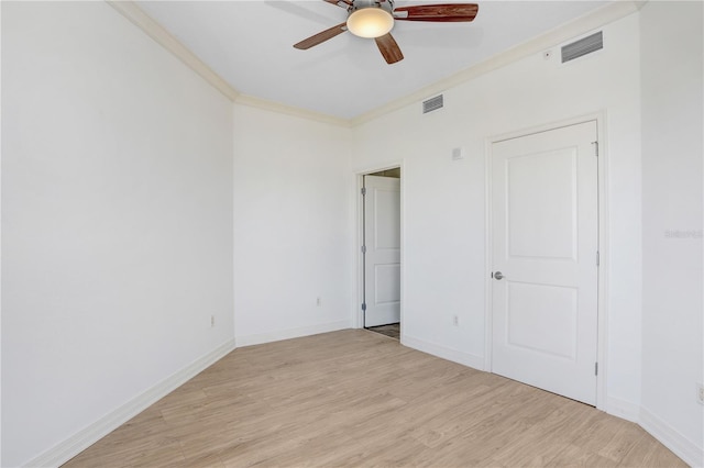 unfurnished bedroom with baseboards, light wood finished floors, visible vents, and crown molding