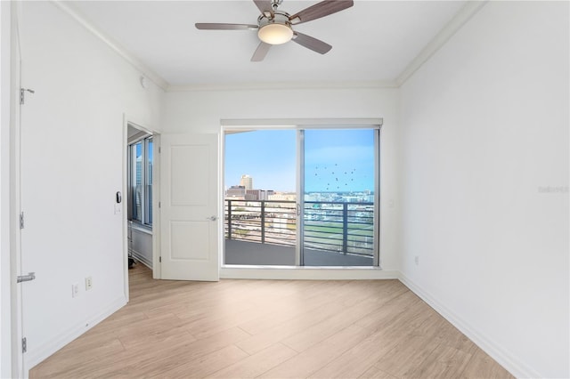 spare room with baseboards, light wood-type flooring, and crown molding