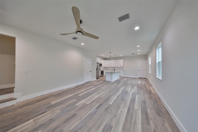 unfurnished living room with baseboards, visible vents, ceiling fan, light wood-type flooring, and recessed lighting