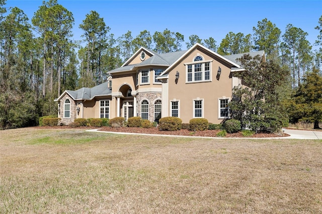 view of front facade featuring stone siding, a front yard, and stucco siding