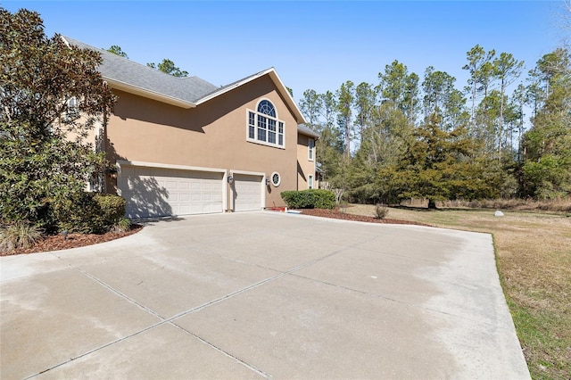 view of home's exterior with a garage, driveway, and stucco siding