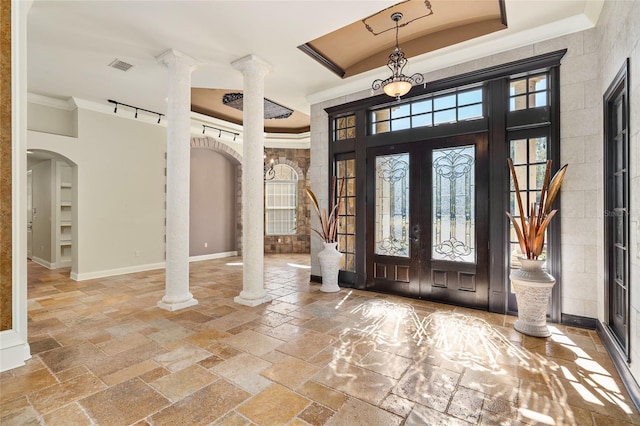 entrance foyer with arched walkways, ornamental molding, stone tile flooring, and decorative columns