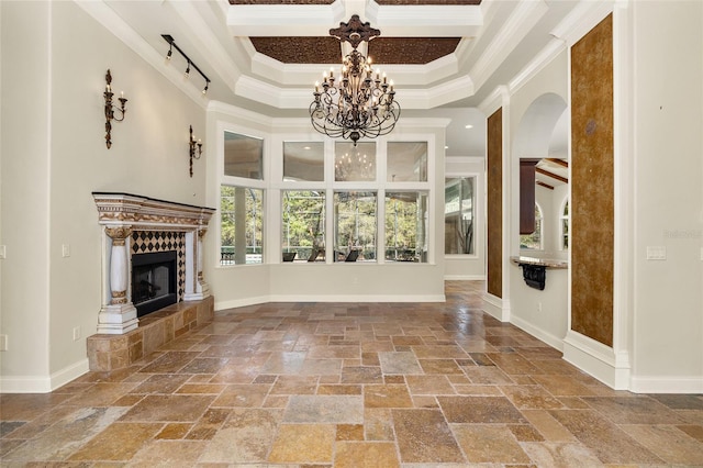 interior space with a chandelier, a fireplace, stone tile flooring, and crown molding