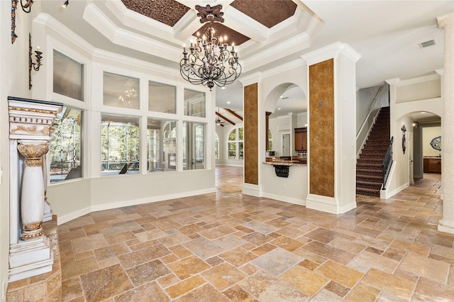 empty room with stone tile floors, a towering ceiling, visible vents, stairs, and crown molding