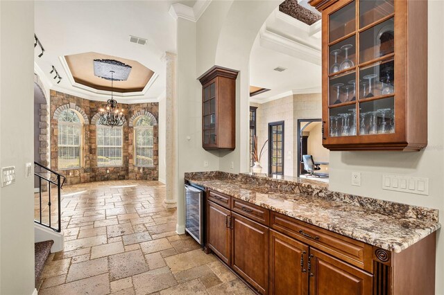 kitchen with visible vents, wine cooler, stone tile flooring, and crown molding