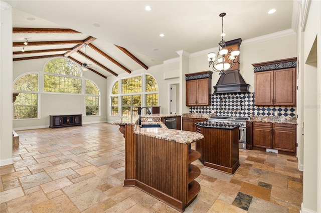 kitchen featuring a sink, appliances with stainless steel finishes, an island with sink, stone tile flooring, and custom range hood