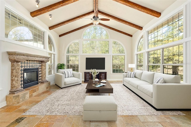 sunroom / solarium with lofted ceiling with beams, a tiled fireplace, and a ceiling fan