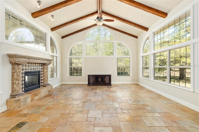 unfurnished living room with high vaulted ceiling, a tiled fireplace, stone tile flooring, and baseboards