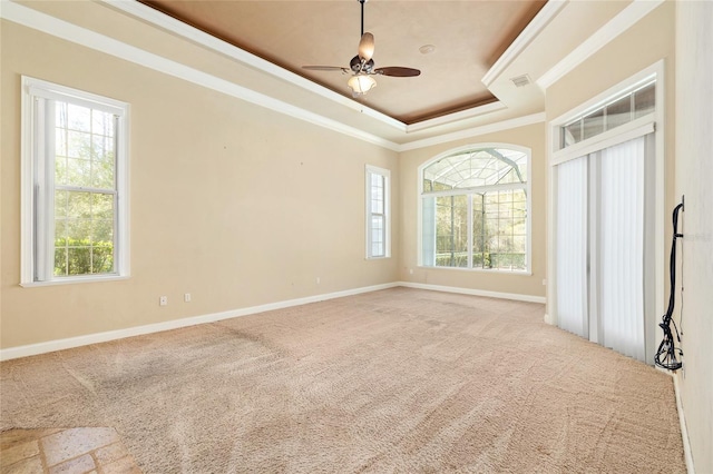 carpeted empty room featuring visible vents, baseboards, a raised ceiling, and crown molding