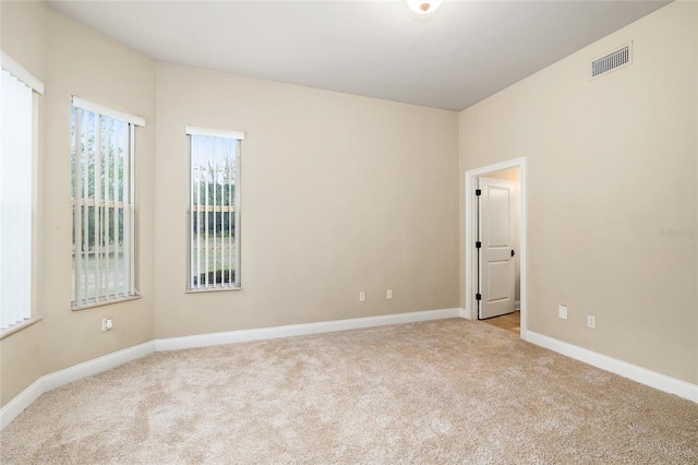 carpeted spare room featuring visible vents and baseboards