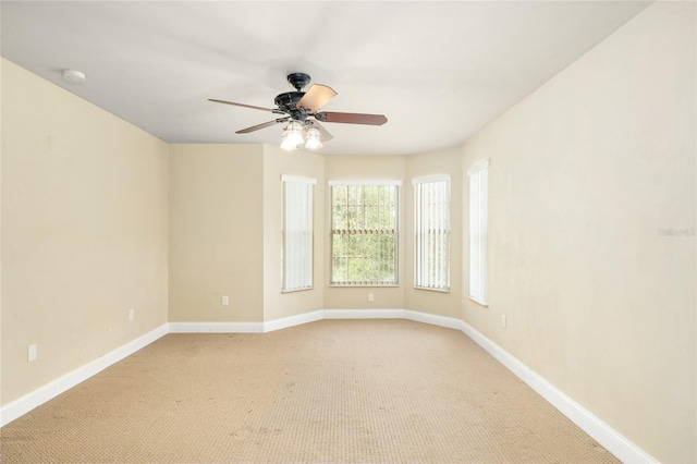 empty room with light carpet, a ceiling fan, and baseboards