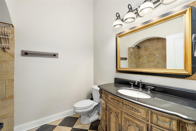 full bath featuring toilet, vanity, tiled shower, baseboards, and tile patterned floors