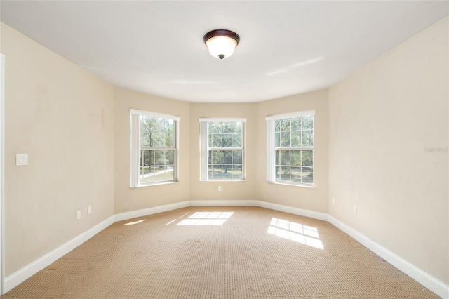 unfurnished room featuring light colored carpet, a healthy amount of sunlight, and baseboards