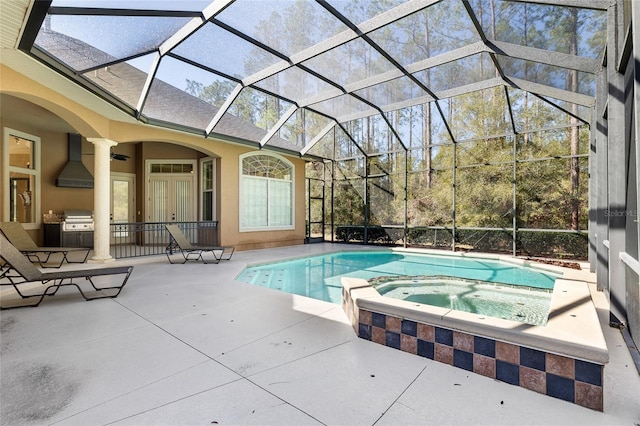 view of swimming pool featuring a patio area, a pool with connected hot tub, glass enclosure, and area for grilling