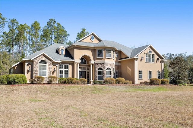 view of front of property with stone siding, a front yard, and stucco siding