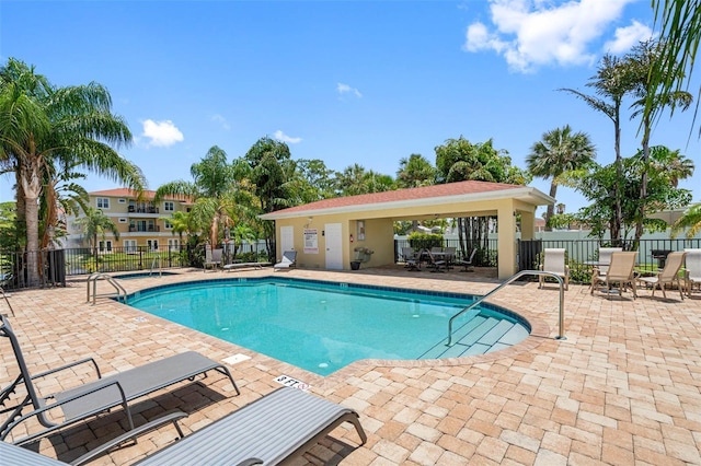 community pool with a patio area and fence