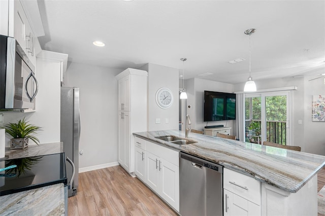 kitchen with a peninsula, light stone counters, stainless steel appliances, and a sink