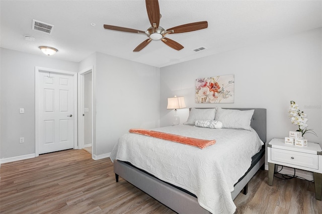 bedroom featuring baseboards, visible vents, ceiling fan, and wood finished floors