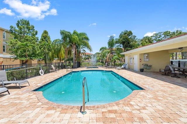 pool with a patio area and fence