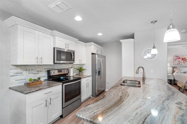 kitchen featuring stone counters, visible vents, appliances with stainless steel finishes, and a sink