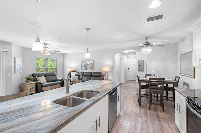 kitchen featuring arched walkways, a sink, visible vents, light wood-style floors, and stainless steel dishwasher