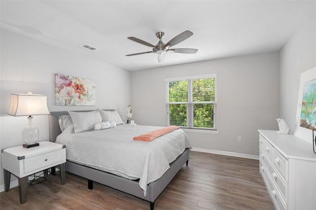 bedroom featuring a ceiling fan, wood finished floors, visible vents, and baseboards