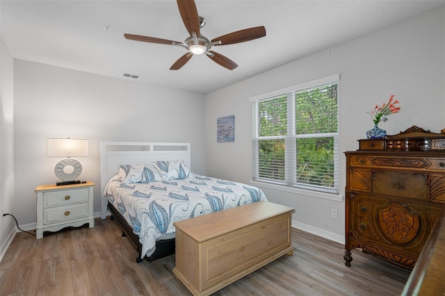 bedroom with light wood finished floors, baseboards, visible vents, and a ceiling fan