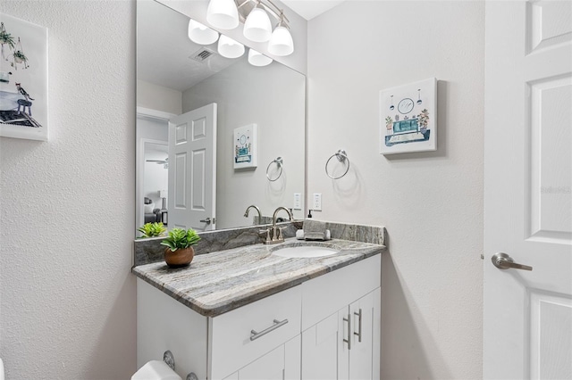 bathroom featuring a textured wall, vanity, and visible vents