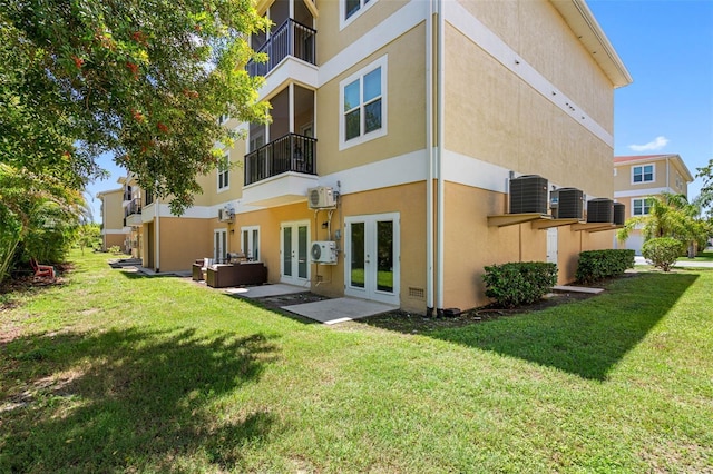 rear view of property featuring french doors, a yard, central AC unit, and stucco siding