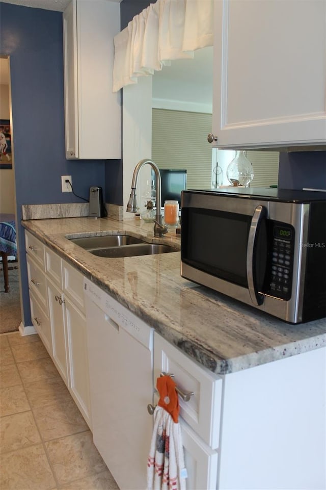 kitchen featuring light stone counters, white dishwasher, a sink, white cabinetry, and stainless steel microwave