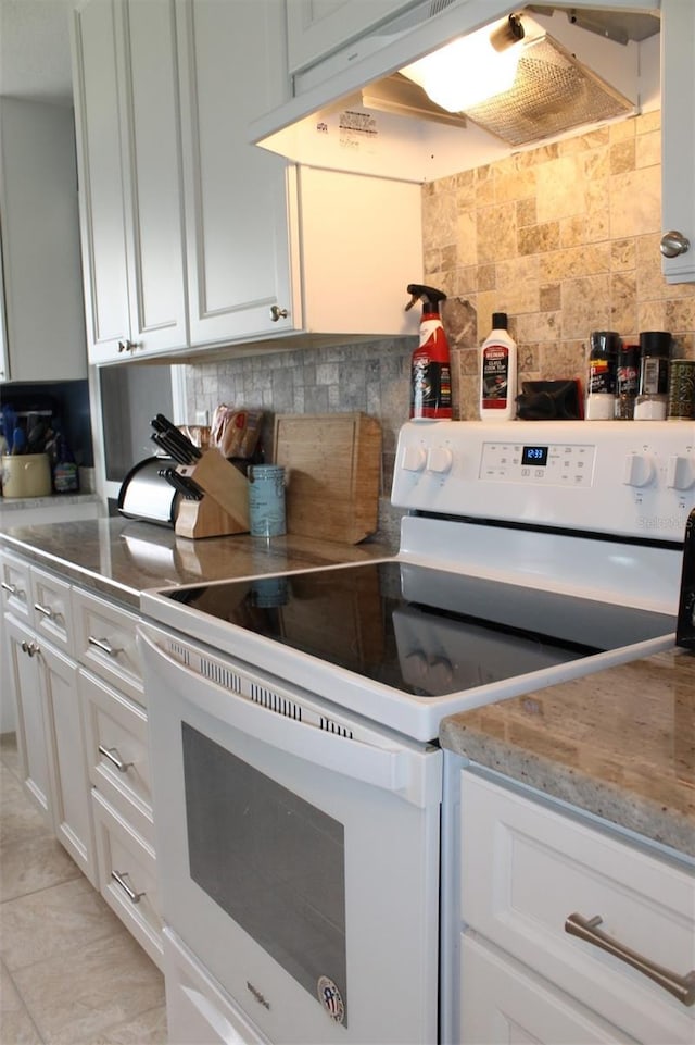 kitchen with light stone counters, electric range, backsplash, white cabinets, and under cabinet range hood