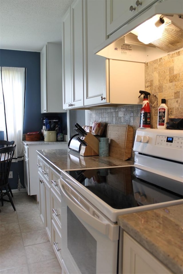 kitchen with under cabinet range hood, white electric stove, and white cabinets