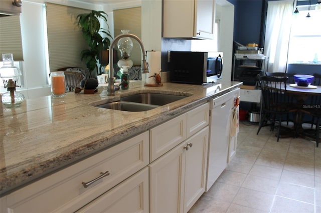 kitchen with light tile patterned floors, white cabinetry, a sink, light stone countertops, and dishwasher