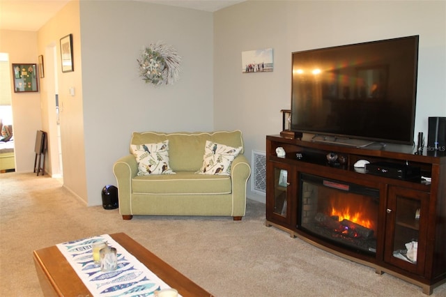 living room featuring visible vents, a glass covered fireplace, and light colored carpet