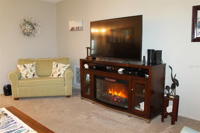 living room featuring a glass covered fireplace, light colored carpet, and visible vents