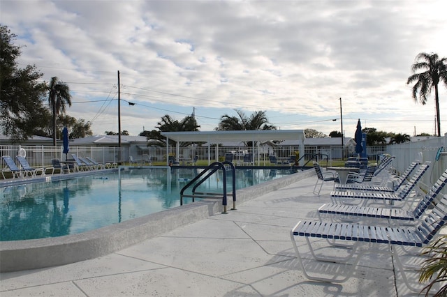 community pool with a patio area and fence