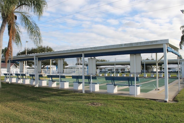 view of property's community featuring a lawn and shuffleboard