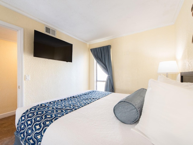 bedroom with a textured wall, visible vents, crown molding, and baseboards