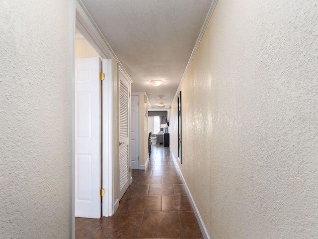 corridor featuring crown molding, a textured wall, a textured ceiling, and baseboards