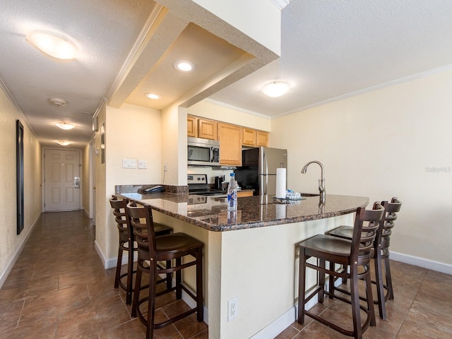 kitchen with stainless steel appliances, a sink, a textured ceiling, and a breakfast bar area